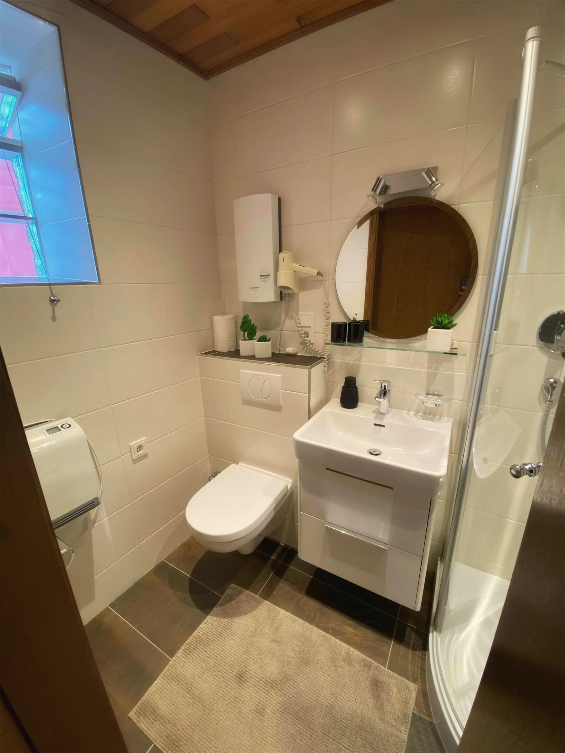 Bad mit Dusche, Waschbecken und rundem Spiegel