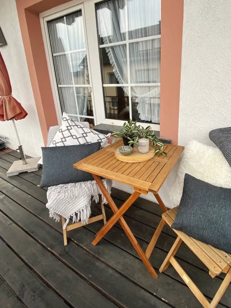 Balkon mit Holztisch, Stühlen und Kissen