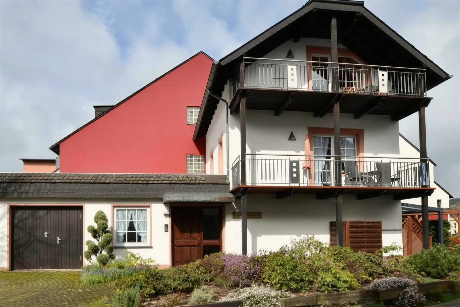 Das Haus mit Holzbalkonen und Vorgarten