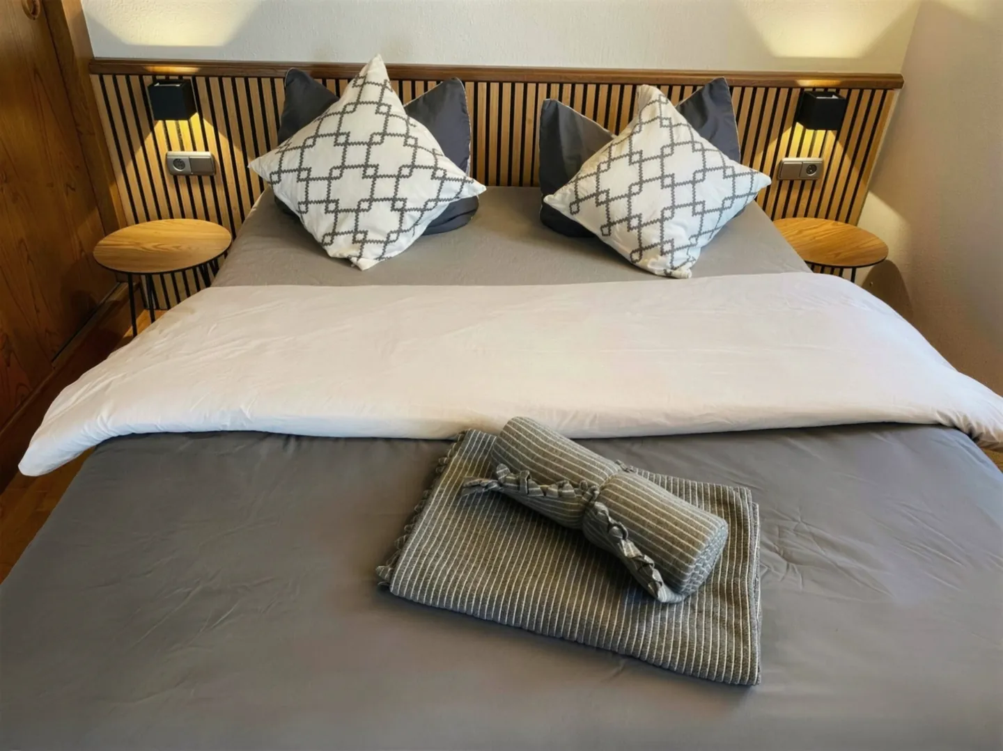 Schlafzimmer mit Doppelbett, weißer Bettwäsche und Holz-Kopfteil